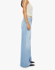 Woman wearing light blue wide-leg jeans and a white top on a white background
