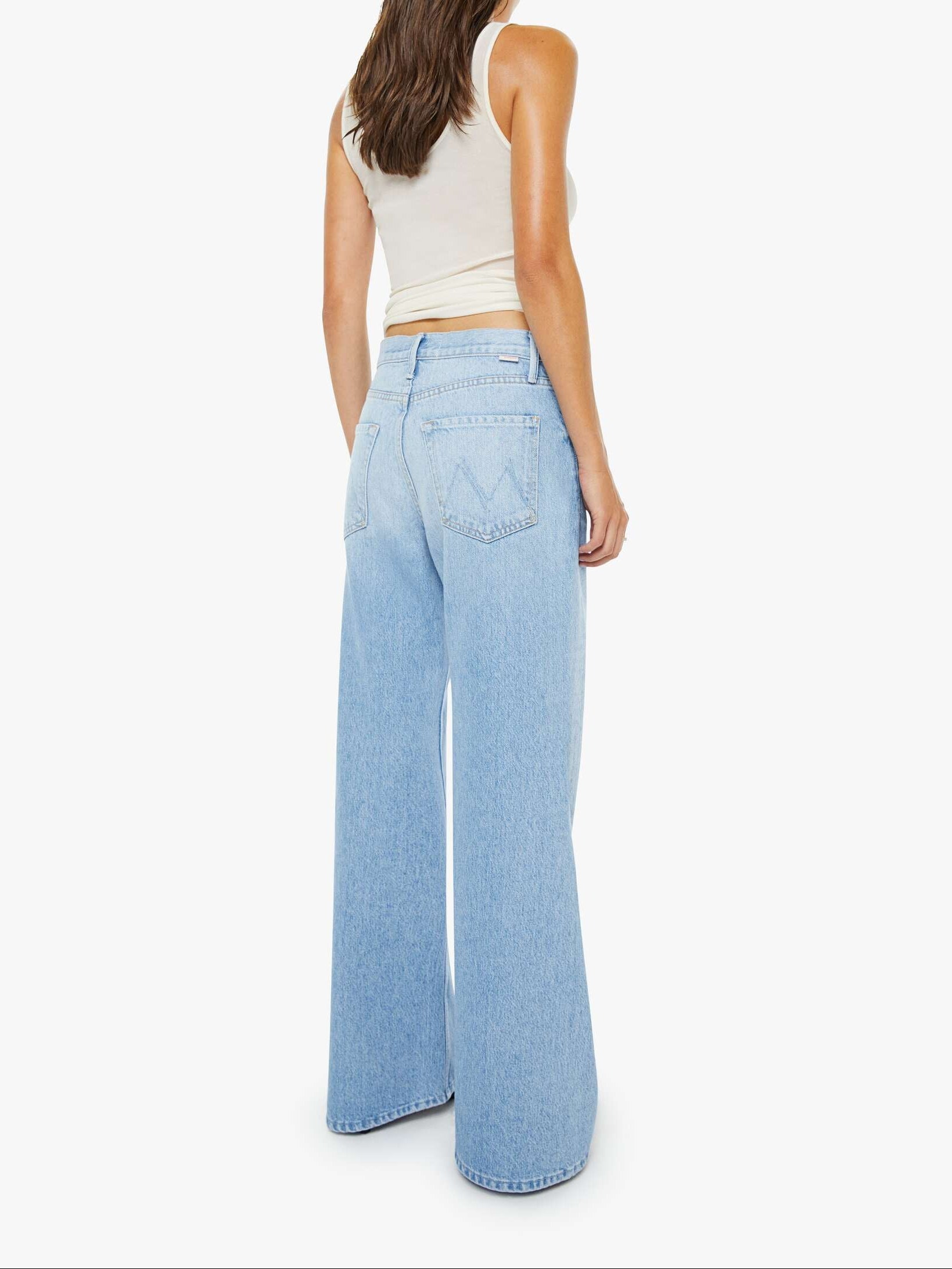 Woman wearing light blue jeans and a white top on a white background