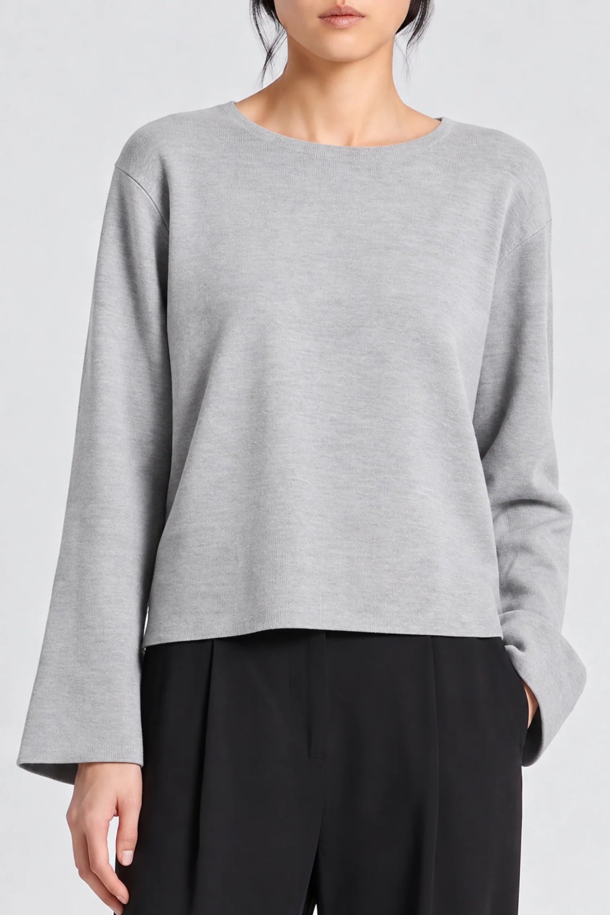 model wearing a grey long sleeve sweater and black pants on a grey background 