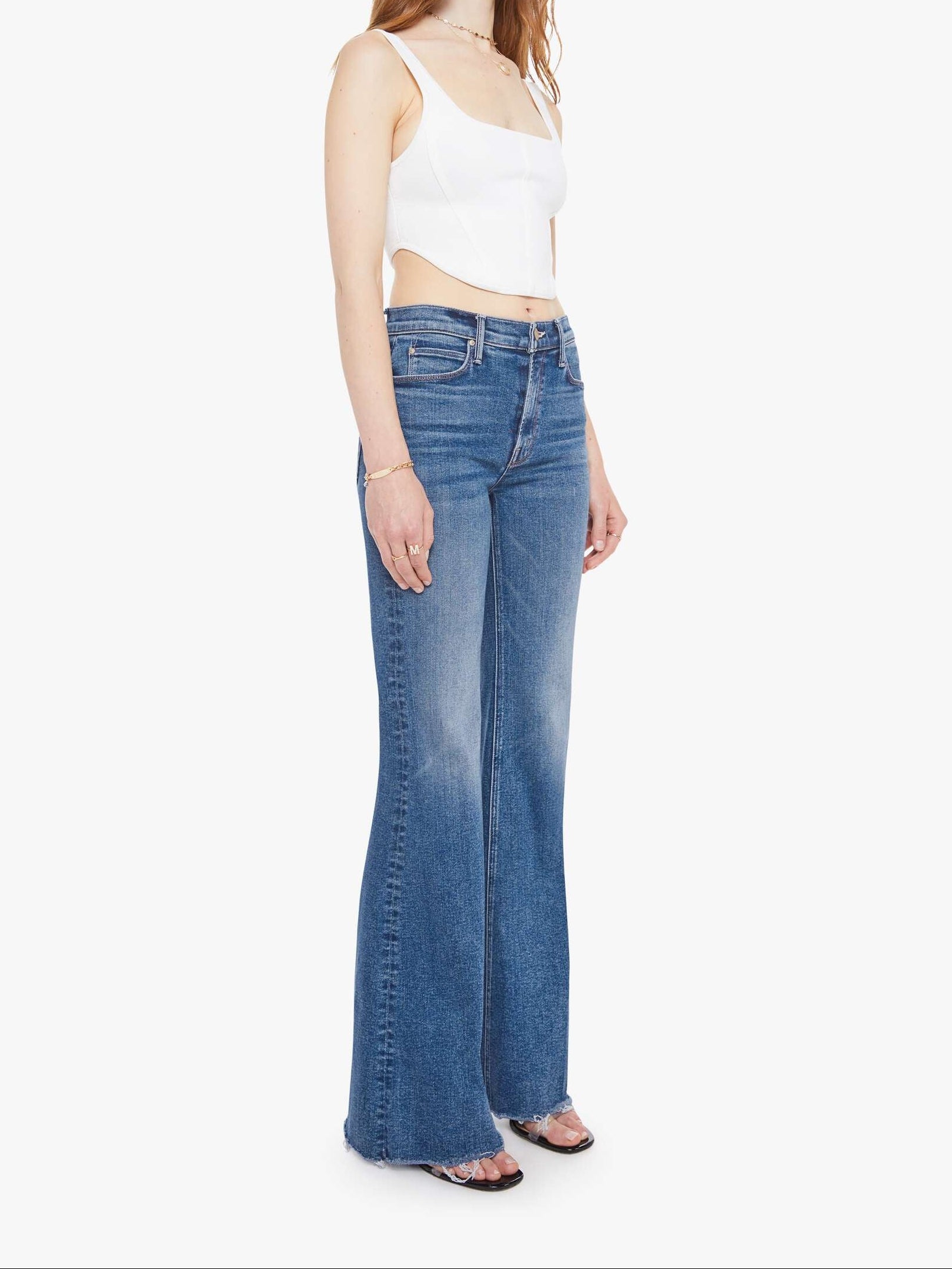 Woman wearing a white top and blue jeans on a white background. side/front view