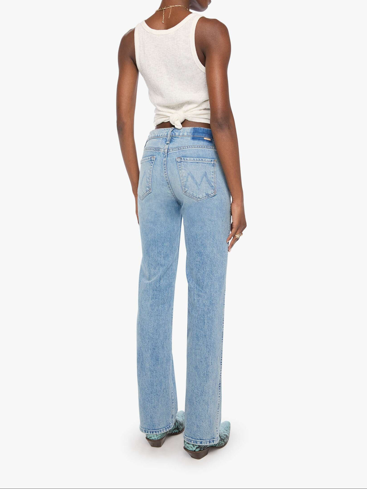 Woman wearing light blue jeans and a white sleeveless top on a white background