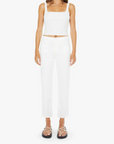 Woman wearing a white sleeveless top and high-waisted pants on a white background