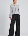 model wearing a grey long sleeve sweater and black pants on a grey background 