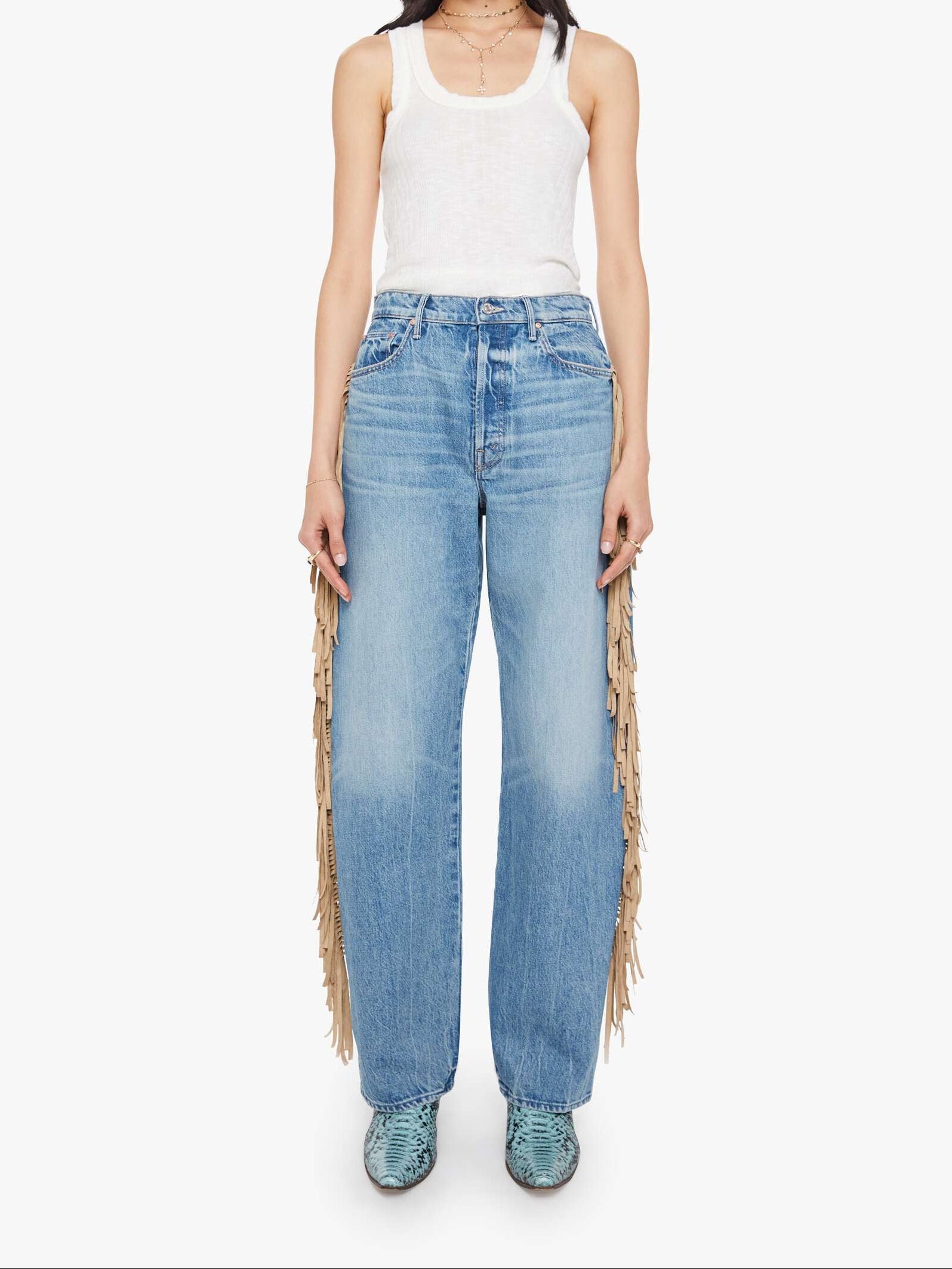 Woman wearing light blue jeans with fringe details on a white background