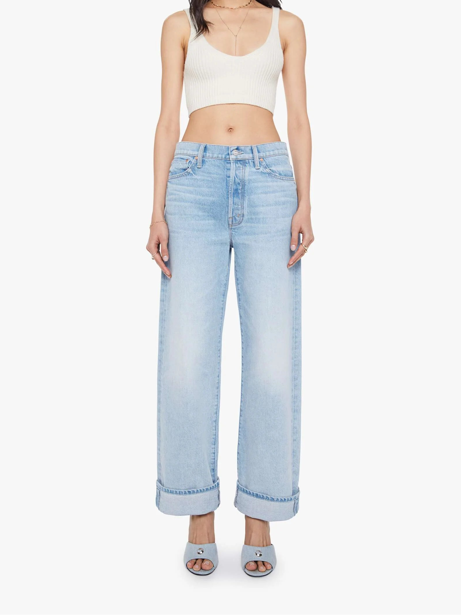 Woman wearing light blue jeans and a white top on a white background