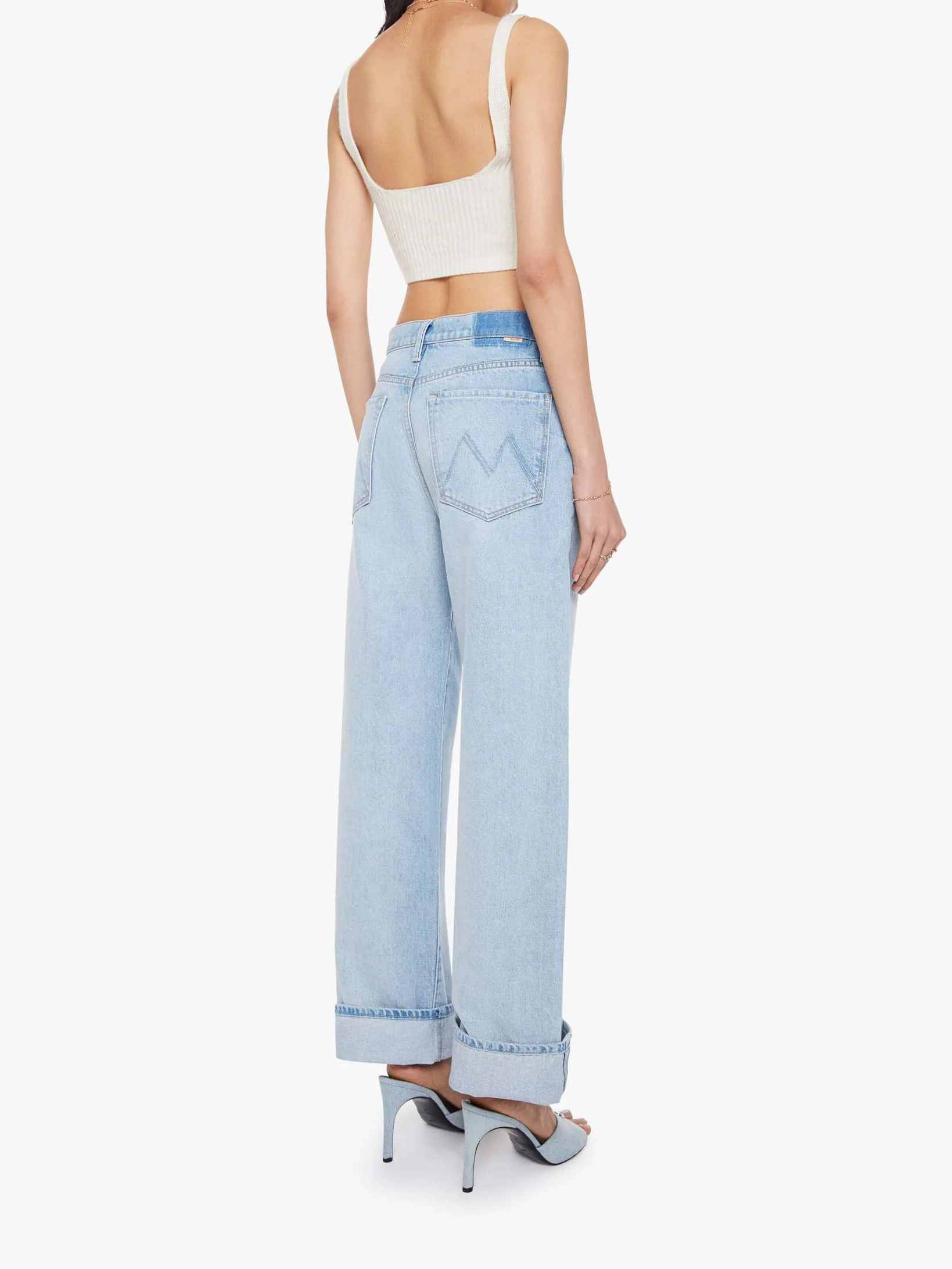 Woman wearing light blue jeans and a white top on a white background