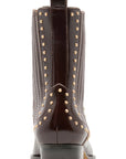 A dark brown leather boot with gold-tone metal studs, shown from the back on a white background.