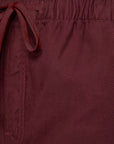 Close-up of a pair of burgundy drawstring shorts showing the textured fabric, waistband, and drawstring loop.