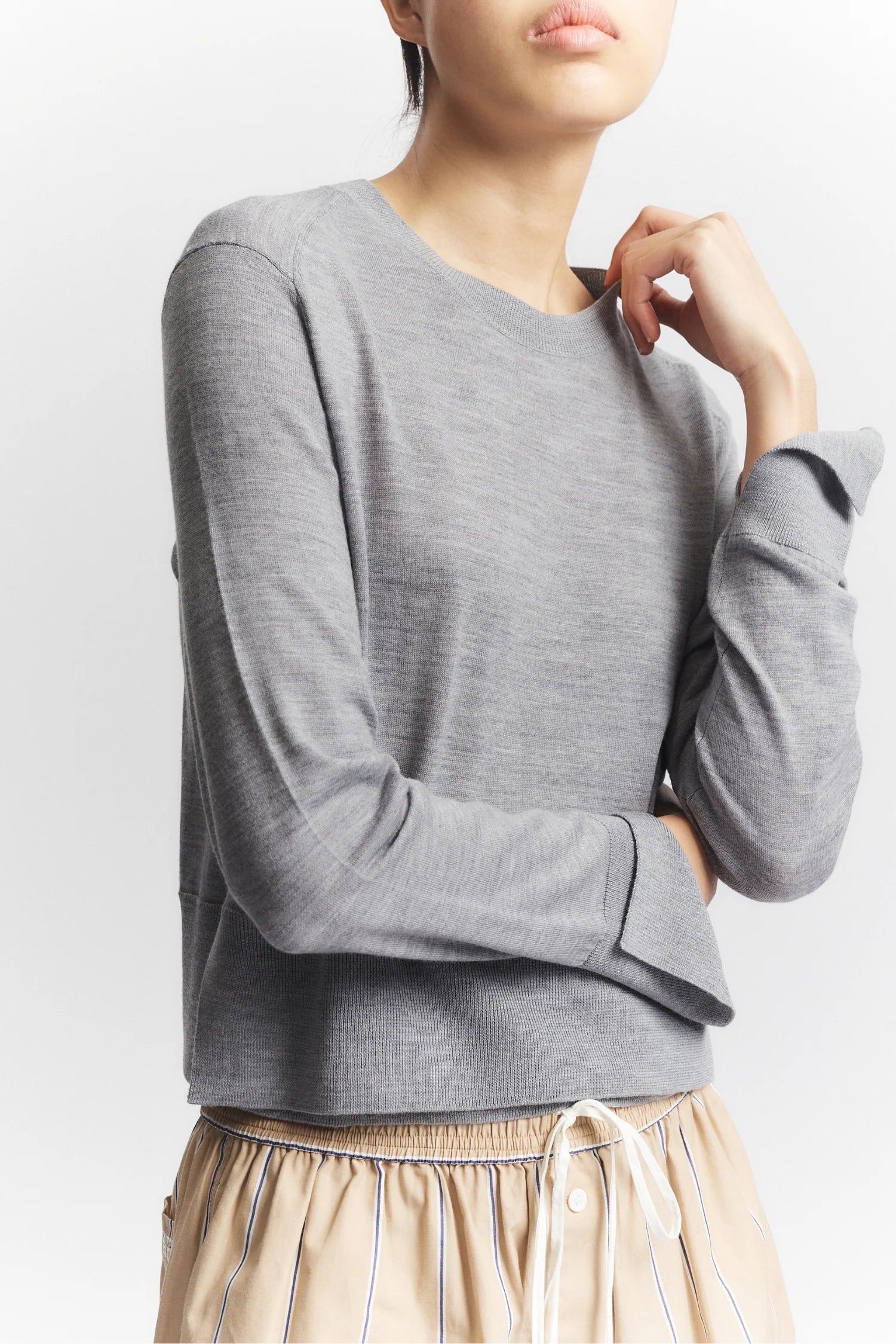 Person wearing a gray long-sleeve top with a plain background