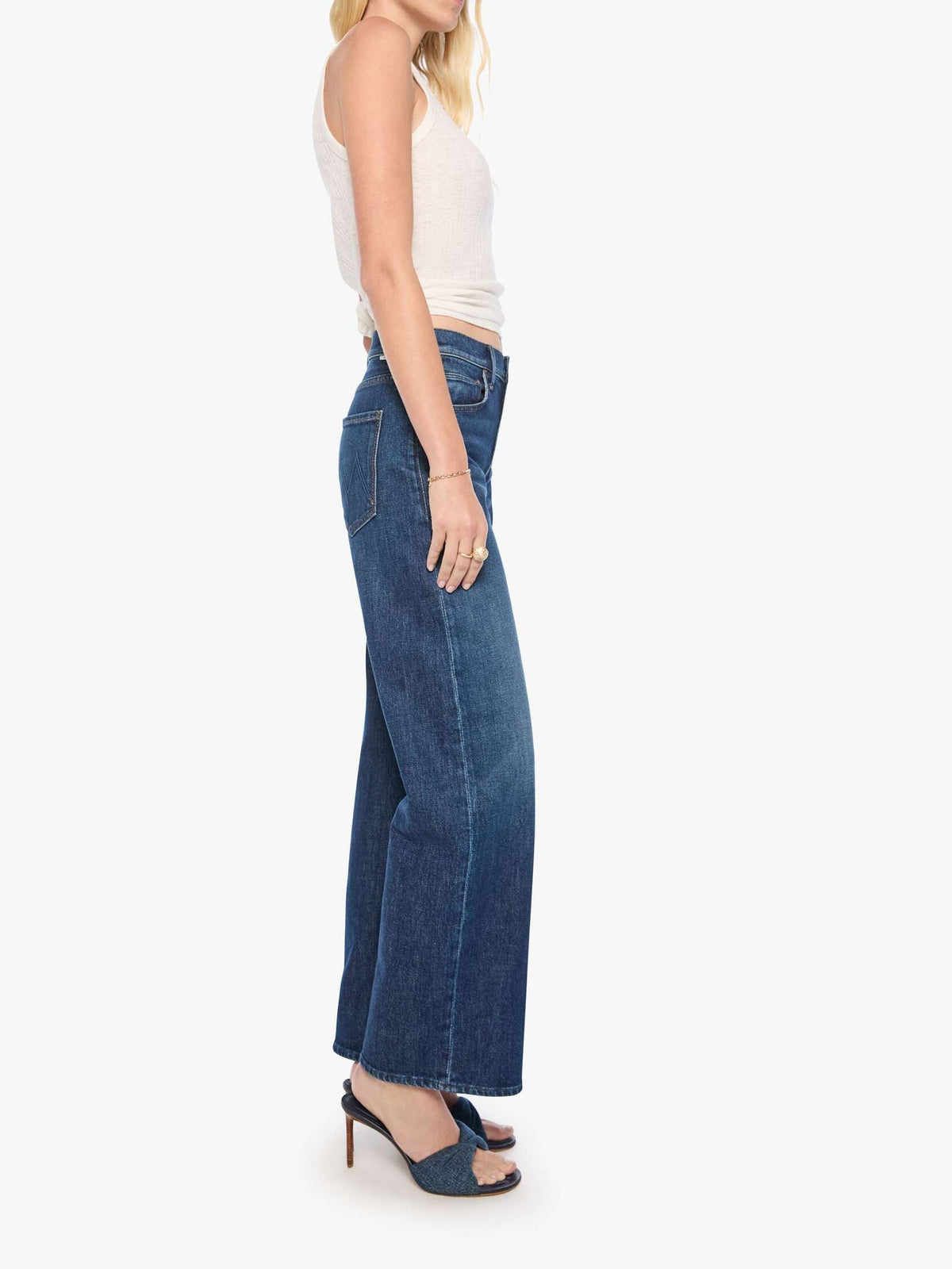Woman wearing blue jeans and a white top on a white background
