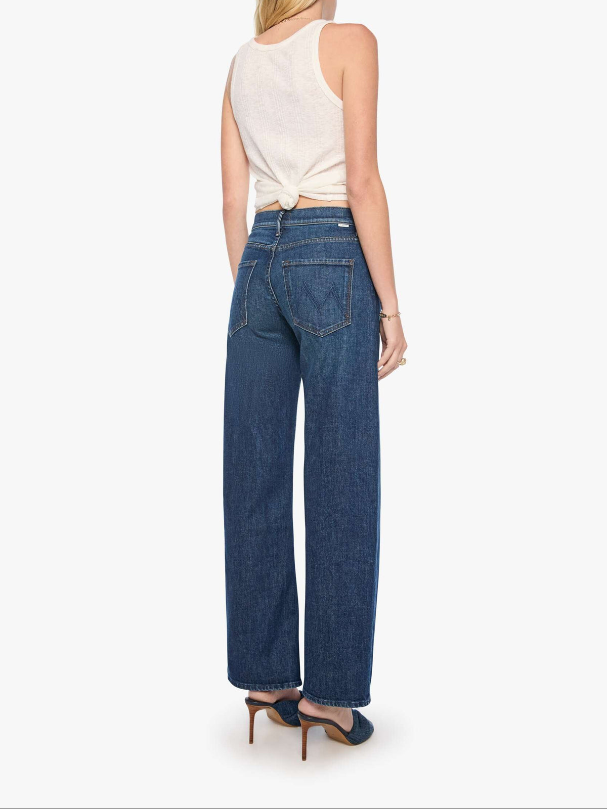 Woman wearing blue jeans and a white top on a white background