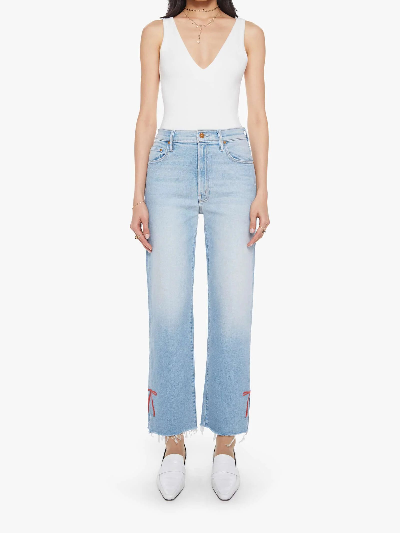 Woman wearing a white sleeveless top and light blue jeans on a white background