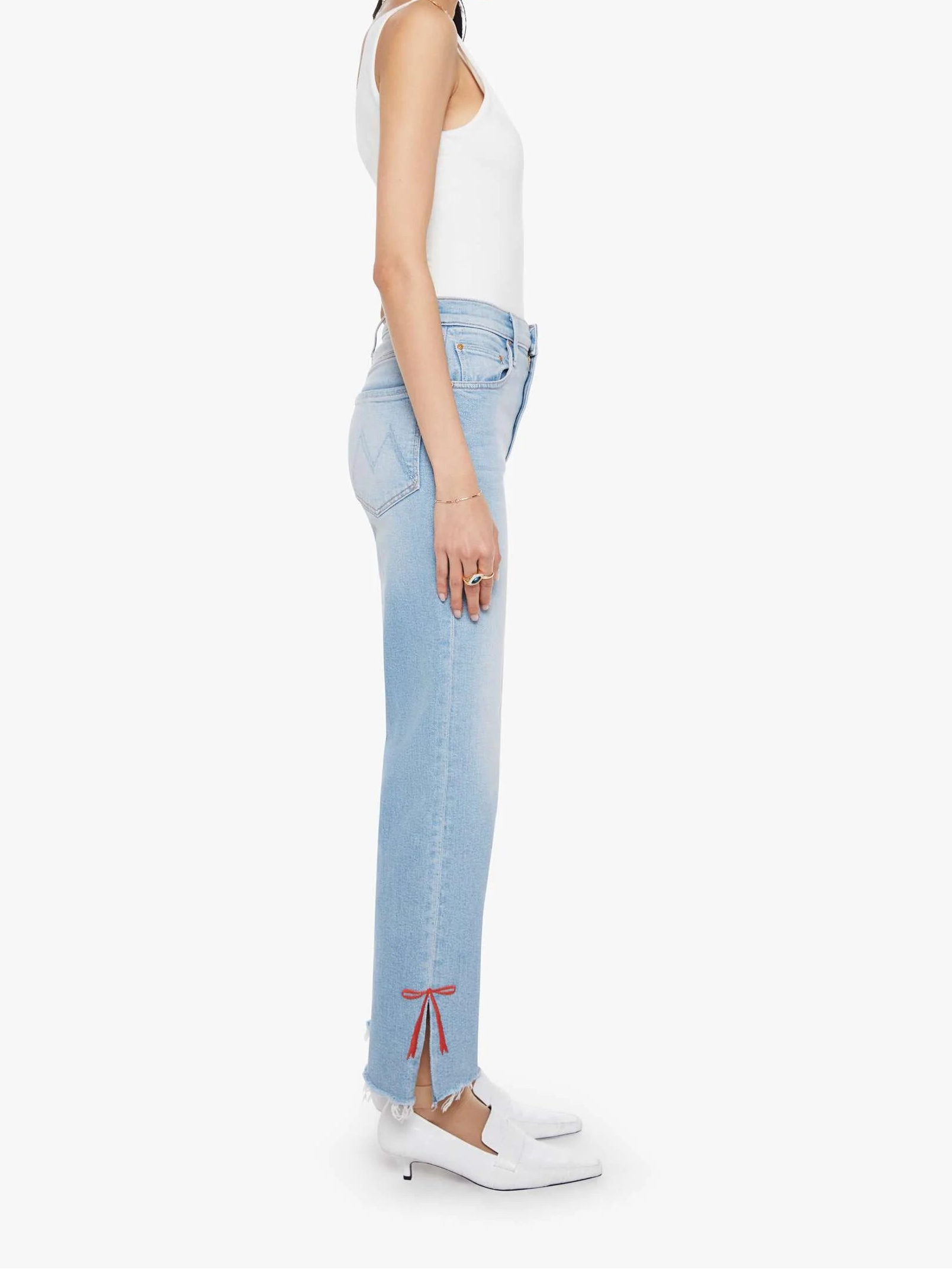 Woman wearing light blue jeans and a white top on a white background