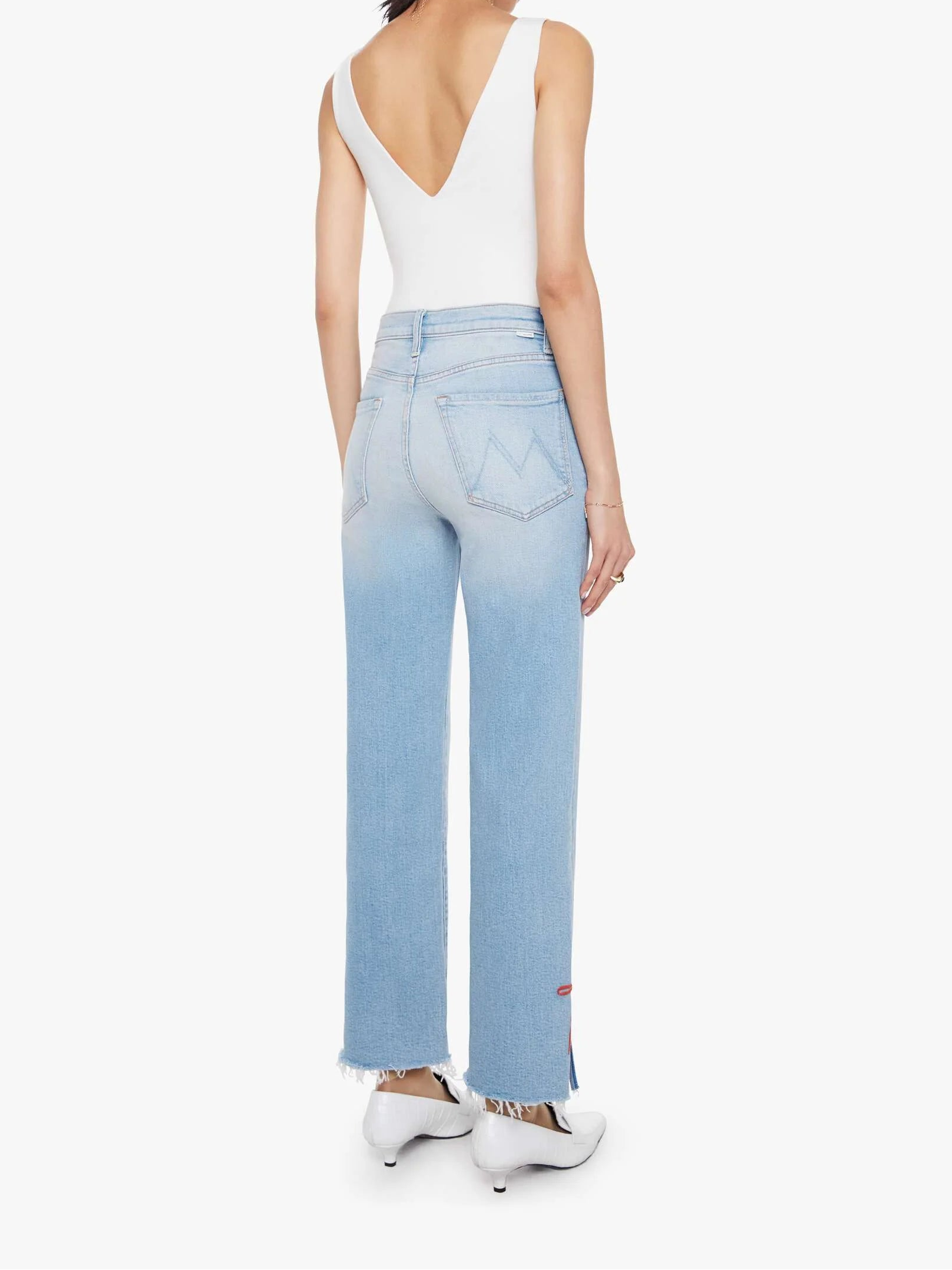 Woman wearing light blue jeans and a white top on a white background