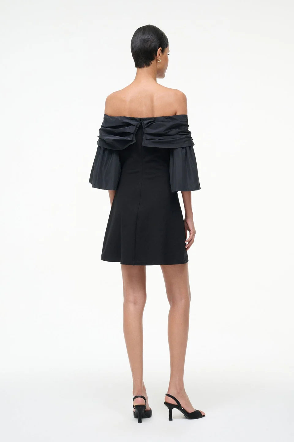 Black off-shoulder dress with ruffled details on a white background, back