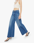 Woman wearing blue jeans and a white top on a white background