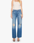 A woman modeling a pair of high-waisted, wide-leg blue jeans with distressed details and a faded wash, paired with a white tank top and sunglasses against a plain white background.