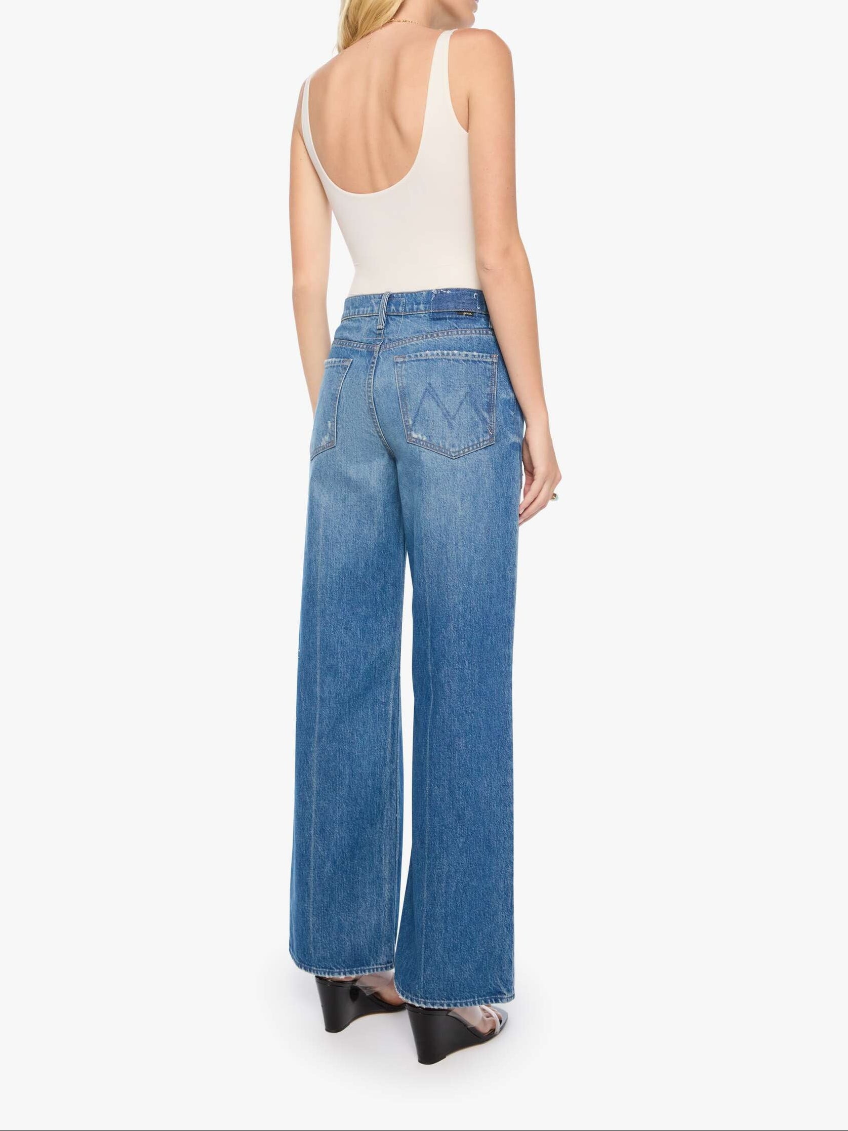Woman wearing blue jeans and a white top on a white background