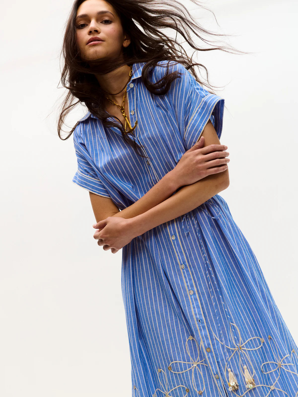 Woman wearing a blue dress with intricate patterns on a white background
