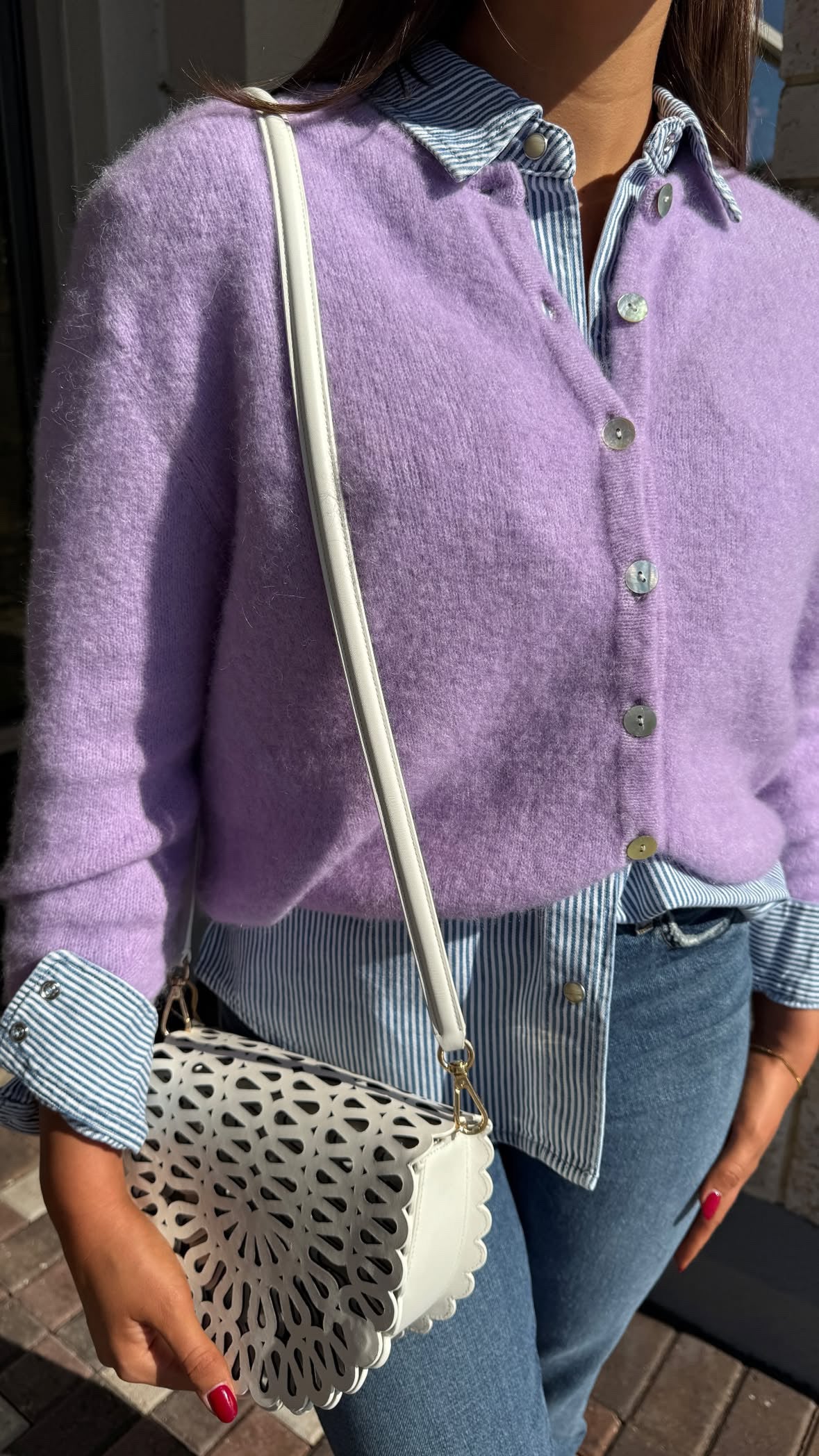 Person wearing a purple cardigan with the Mccall Laser Cut Leather Saddle Bag.