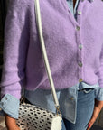 Person wearing a purple cardigan with the Mccall Laser Cut Leather Saddle Bag.