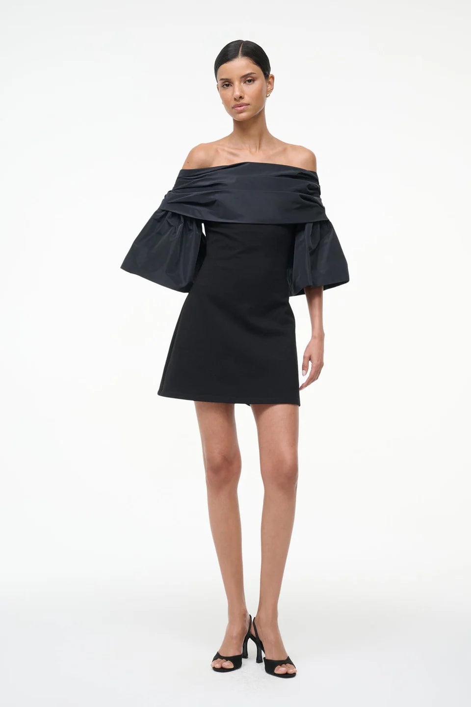 Black off-shoulder dress worn by a model on a white background, front
