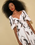 Woman wearing the sol dress with black patterns against a beige background