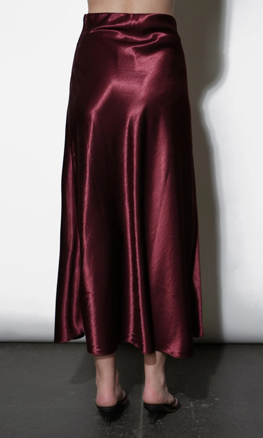 Burgundy satin skirt worn by a person on a white background, back 