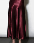 Burgundy satin skirt worn by a person on a white background, back 
