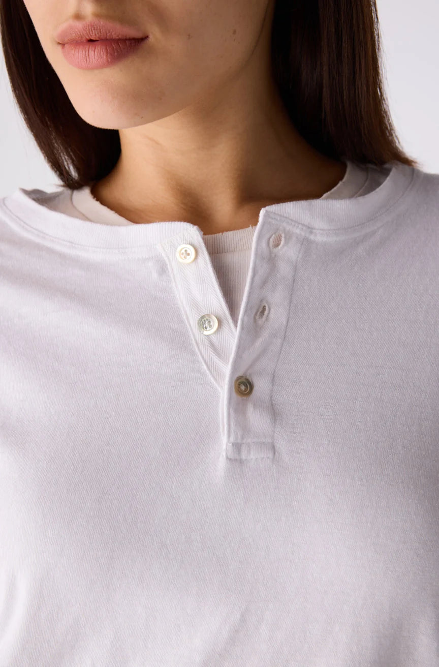 Close-up of a model wearing a white Henley shirt with a three-button placket.