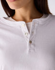Close-up of a model wearing a white Henley shirt with a three-button placket.