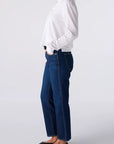 Person wearing a white sweater and blue jeans on a light gray background
