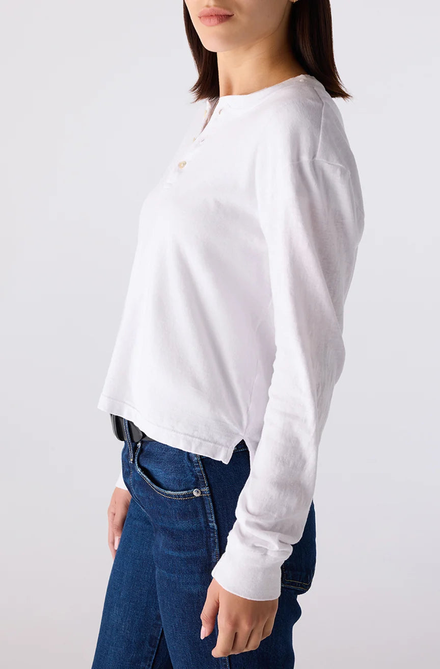 Person wearing a white long-sleeve shirt and blue jeans on a plain background