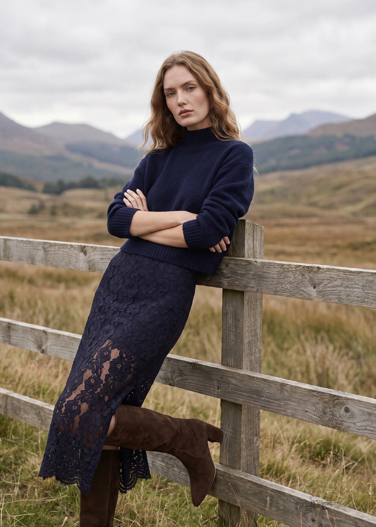 model wearing a navy seater and navy lace skirt leaning on a fence outdoors 