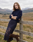 model wearing a navy seater and navy lace skirt leaning on a fence outdoors 