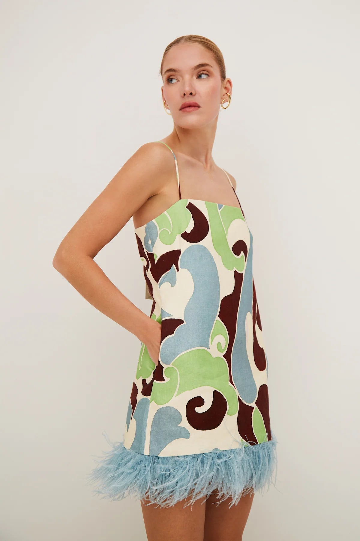 Woman wearing a colorful dress with feathered hem on a plain background