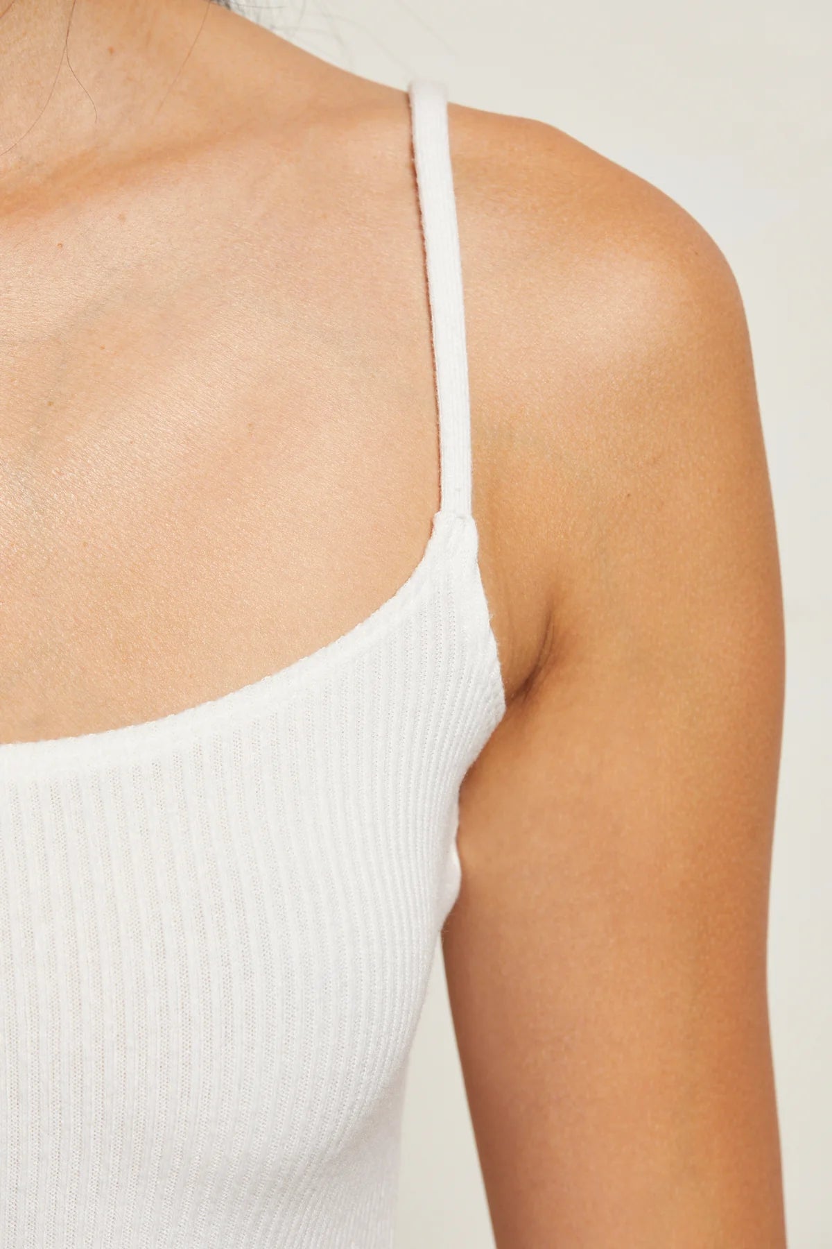 White ribbed tank top worn by a person on a plain background