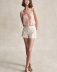 Woman wearing a pink sleeveless top and floral shorts on a beige background, full body
