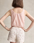 Person wearing a pink sleeveless top and floral shorts against a neutral background, back view