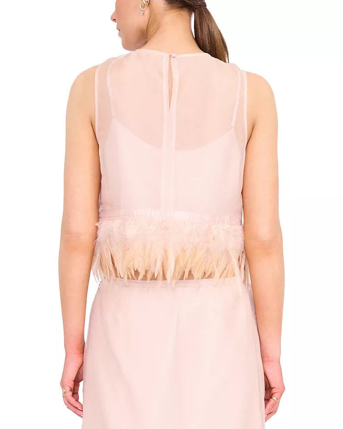 A woman shown from the back wearing a sleeveless blush pink dress with a sheer upper back panel, feathered trim at the waist, and a flowing skirt against a plain white background.