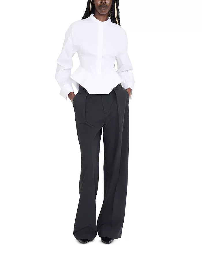 A model wearing a white long-sleeve button-up shirt with a structured peplum waist and black wide-leg trousers, standing against a plain white background.