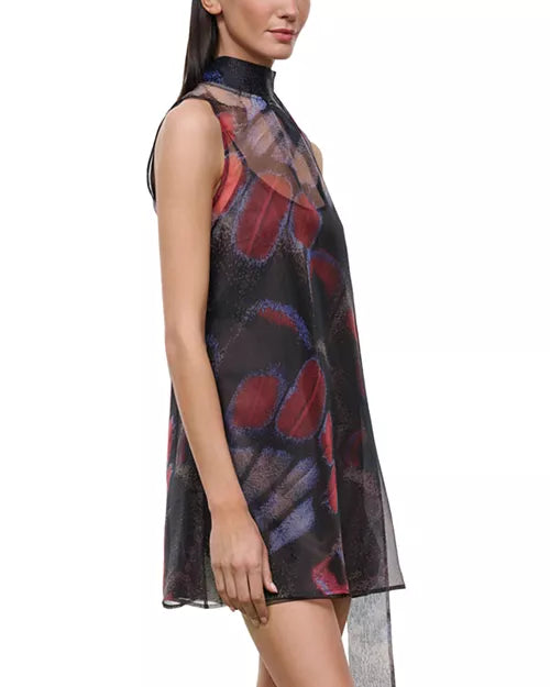 A sleeveless high-neck sheer dress with an abstract butterfly-wing style print in red, purple, and blue over a black base, shown on a model against a white background.