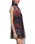 A sleeveless high-neck sheer dress with an abstract butterfly-wing style print in red, purple, and blue over a black base, shown on a model against a white background.