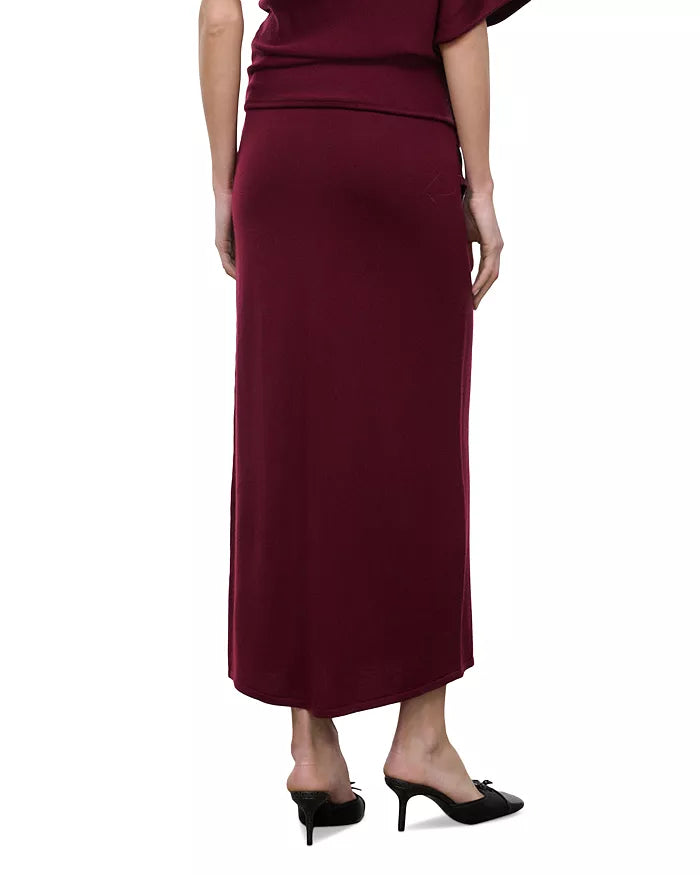 A woman wearing a long, dark burgundy maxi skirt with a matching top and black pointed-toe mule heels, shown from the back against a plain white background.
