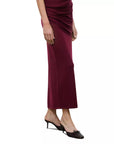 A model wearing a draped, floor-length wine red maxi skirt with black pointed-toe mule heels, shown from the waist down on a plain white background.