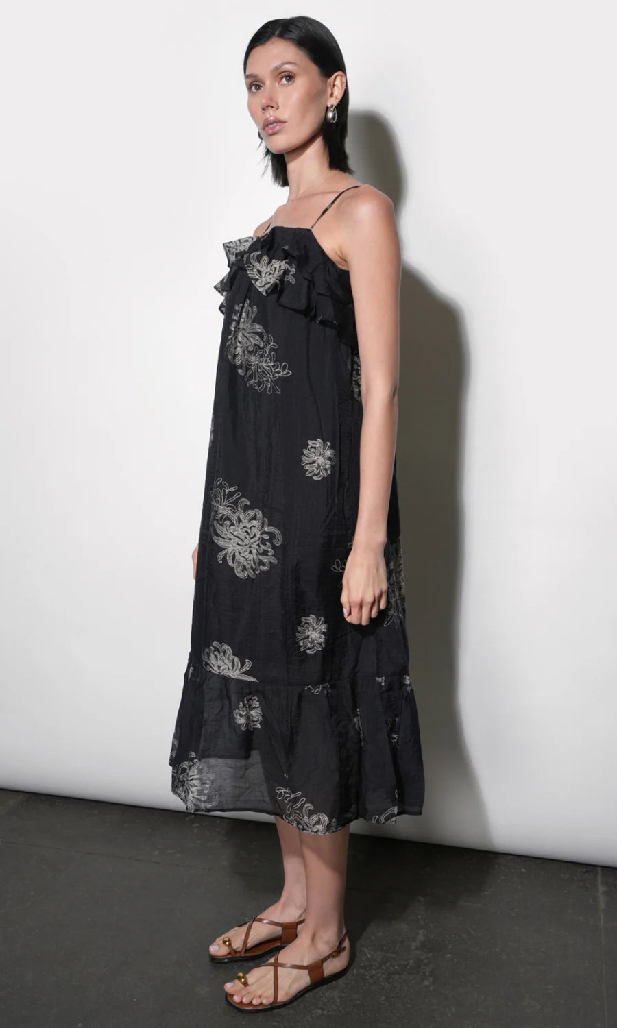 model wearing the Paige Layered Ruffle Midi Dress with strappy sandals on a white background, side