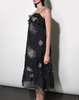 model wearing the Paige Layered Ruffle Midi Dress with strappy sandals on a white background, side