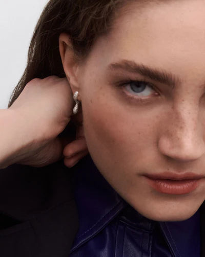 Close-up of a woman wearing earrings with a neutral background