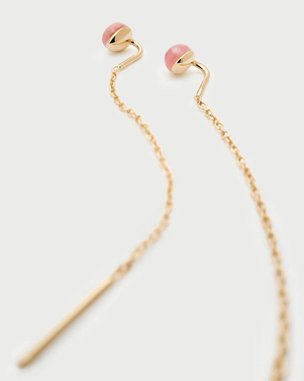 Gold earrings with pink stones on a white background