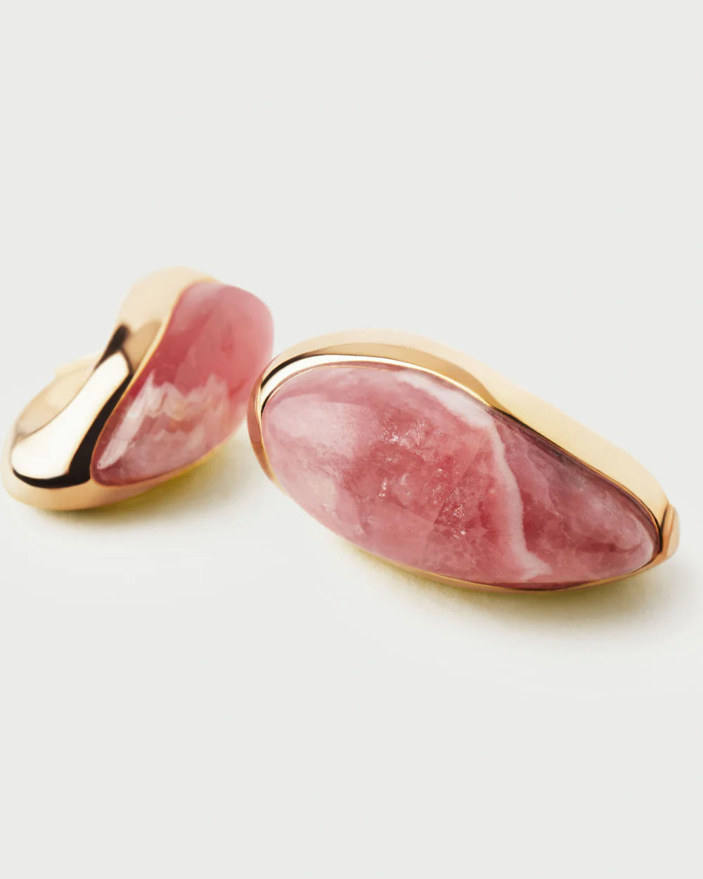 Pair of earrings with pink stone and gold accents on a white background